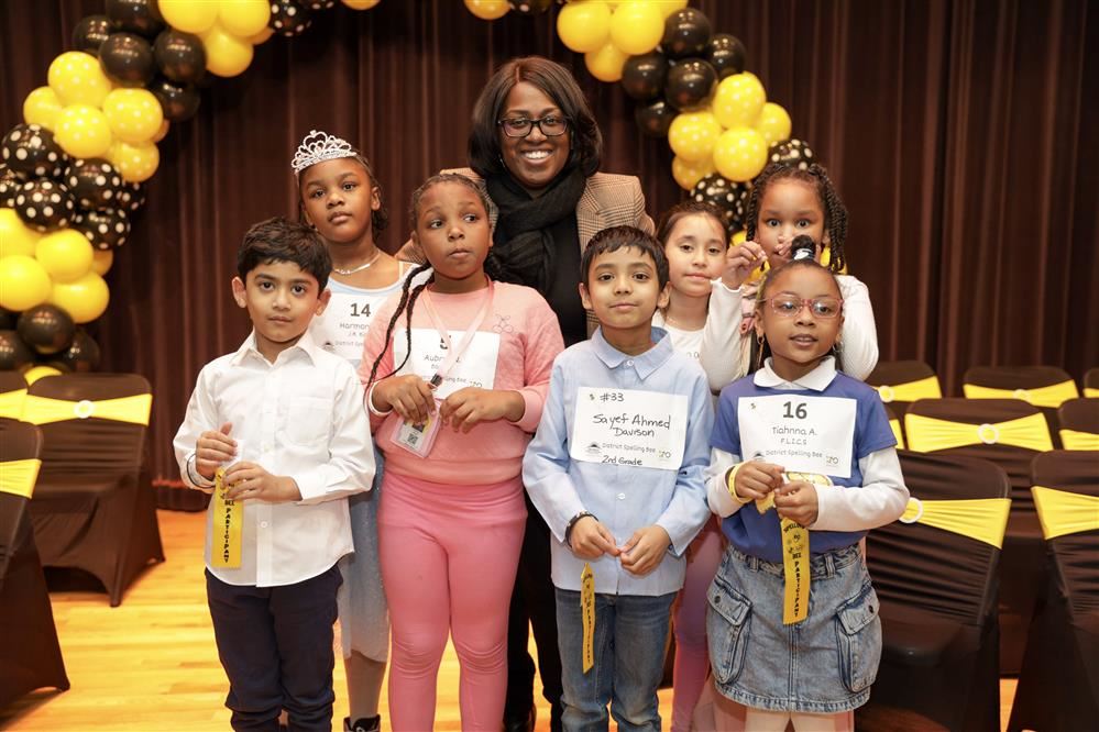  Spelling Bee participants and administrator standing together in a group and smiling 
